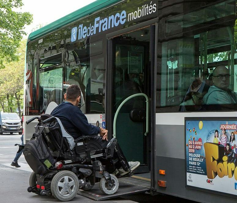 Usager de fauteuil roulant montant à bord d'un bus Île-de-France Mobilités ayant déployé sa rampe d'accès