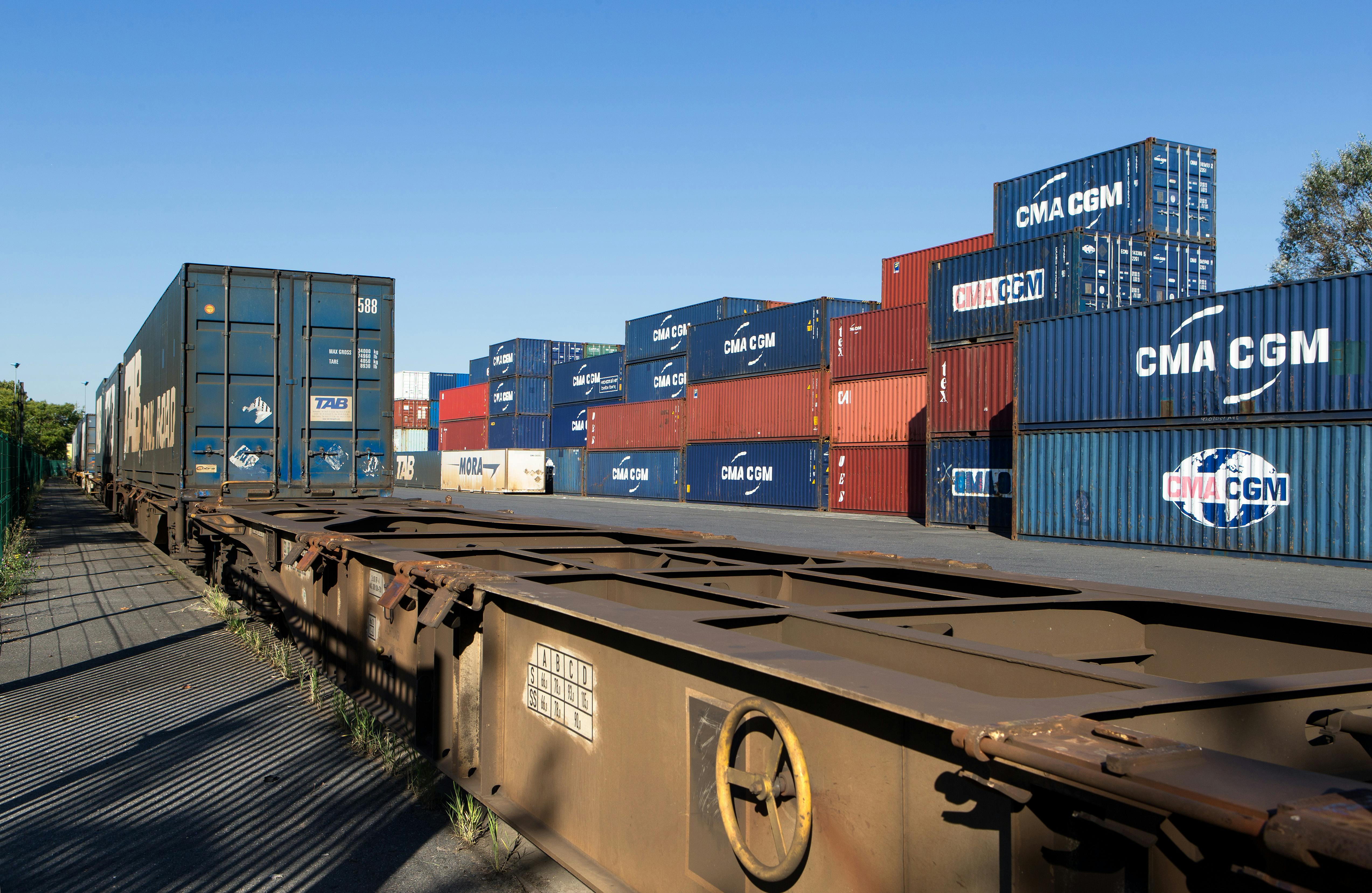 Conteneurs CMA/CGM entreposés, partiellement chargés sur un train de fret