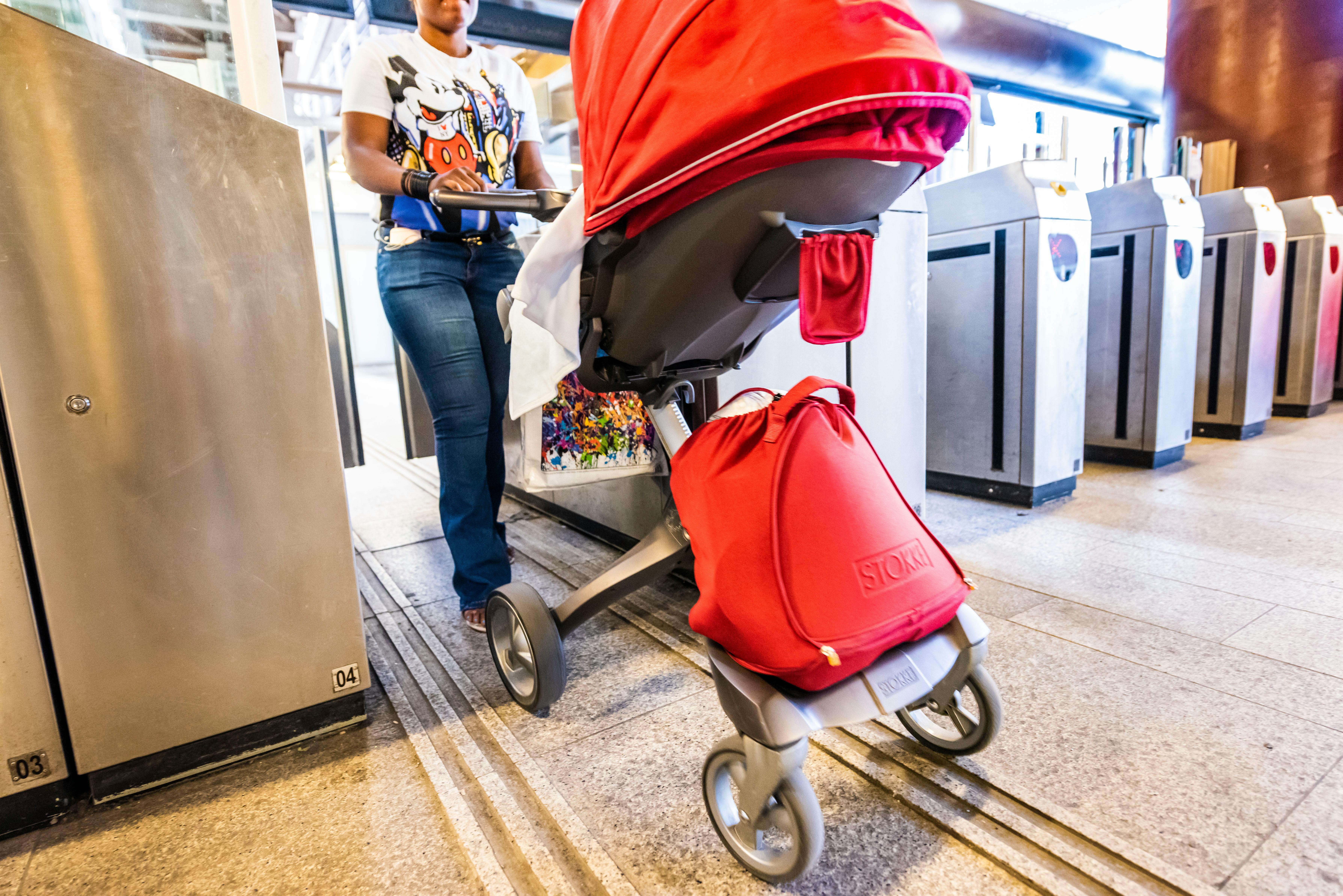 Femme traversant un valideur dans le réseau de métro avec une poussette